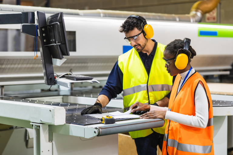 Man and young girl in high vis and ear defenders working in manufacturing plant