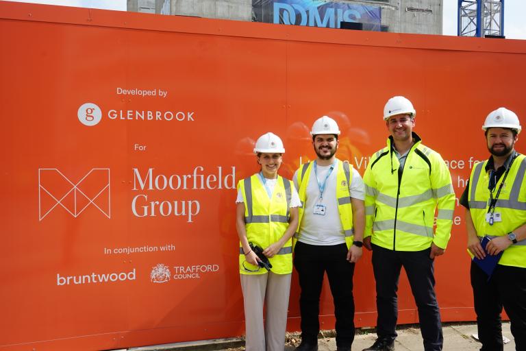 Four people stood in front of an orange constuction sign